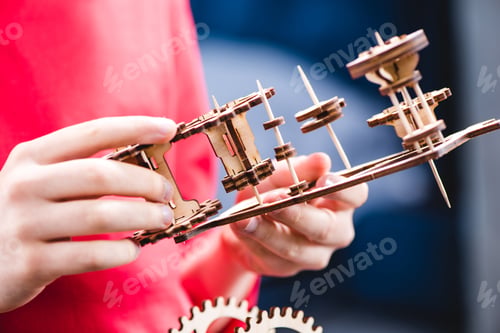 Preview: Partial view of kid holding wooden gear mechanical toy