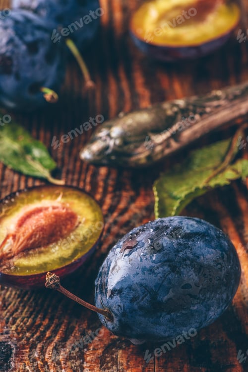 Preview: Ripe plums with leaves, water drops and knife