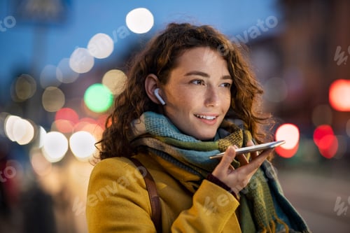 Preview: Woman sending voice note on city street in winter night