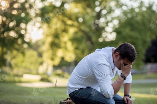Preview: Closeup shot of a male down on the ground with his hand on the face and a blurred background