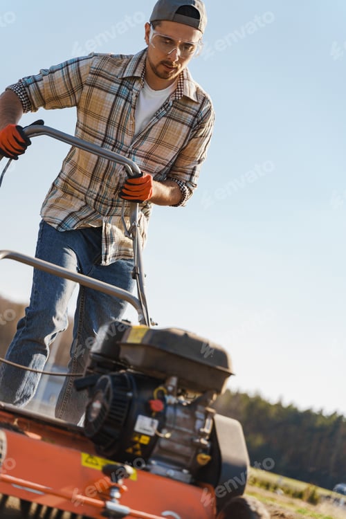 Preview: Man using aerator machine to scarification and aeration of lawn or meadow