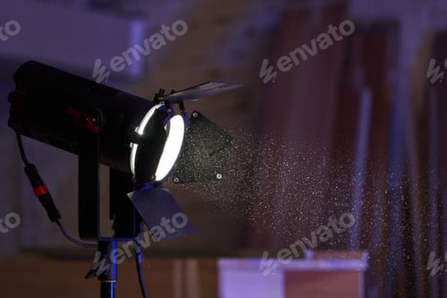 Preview: professional lighting fixture with light-shaping curtains shines a beam through dust particles in