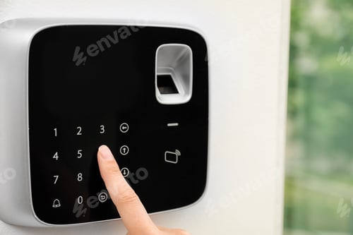 Preview: Young woman entering code on alarm system keypad indoors