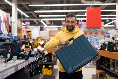 Preview: Satisfied buyer of a power tool store holding a case with a smile