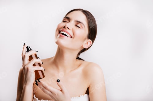 Preview: Attractive adult woman without make-up sprays fragrant oil onto her body. Lady in towel posing on w