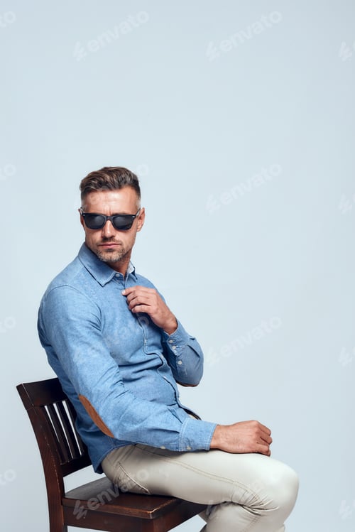 Preview: I need to think. Side view of serious bearded man in casual clothes and eyewear adjusting his shirt