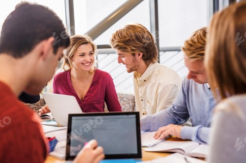 Preview: Happy young friends studying together at table in university