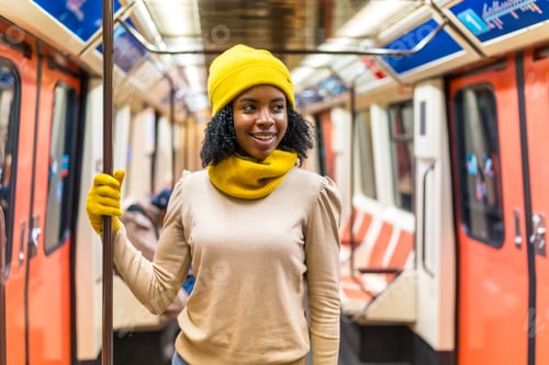 Vista previa: Young woman traveling by subway holding handrail and smiling