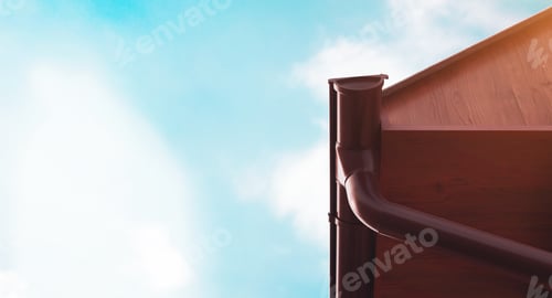Roof Gutter System Against A Cloudy Blue Sky