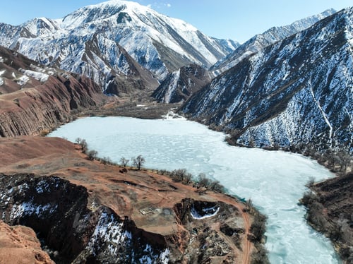 Preview: Frozen lake and red canyon walls beneath towering snowy mountains