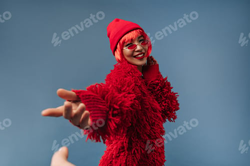 Preview: Pretty asian lady with short red hairstyle and cool sunglasses in trendy cap and long sleeve sweate