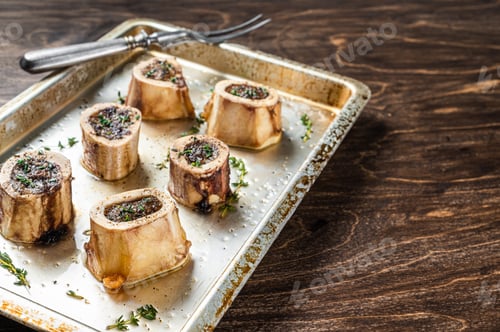 Preview: Roasted marrow beef bones in baking dish. Wooden background. Top view. Copy space