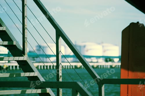 Preview: Closeup of a staircase on a ship on the sea surrounded by factories