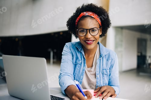 Preview: Smiling young African female entrepreneur working on her business