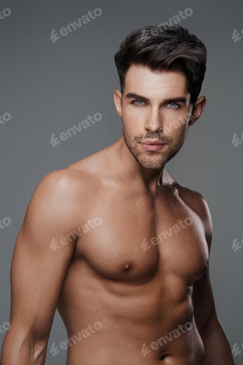 Preview: Close-up portrait of a sexy brunette male model with a bare torso against a gray background