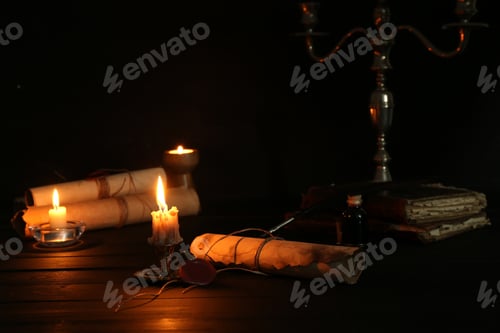 Preview: Many old rolled scrolls and burning candles on black wooden table, closeup