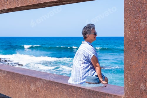 Preview: Portrait of pensive senior woman at beach looking away. Retired enjoying summer holiday at sea