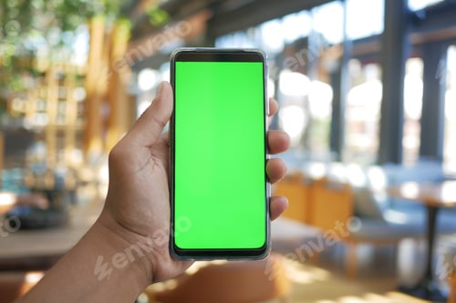 Preview: young man hand using smart phone with green screen at cafe