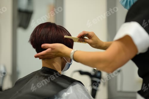 Preview: Closeup shot of a female getting her hair done wearing a face mask - concept of the new normal