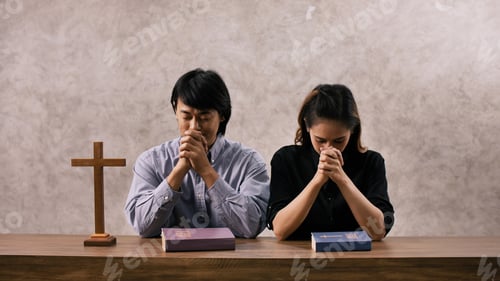 Preview: A young Asian Christian couple praying to Jesus Christ in a church.