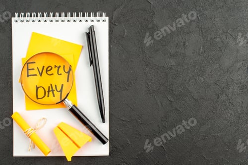 Preview: top view lupa on every day written on sticky note pen scroll sticky note on spiral notebook on dark