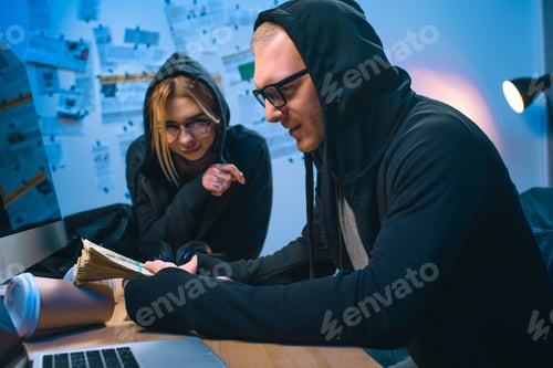 Preview: excited couple of hackers with stack of cash at workplace