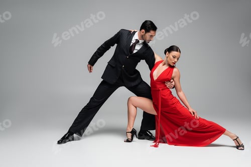 Preview: Man in suit hugging partner while dancing tango on grey background