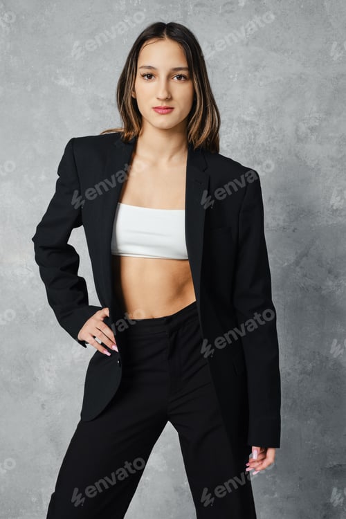 Preview: Young woman in black pantsuit and white top with one arm on waist