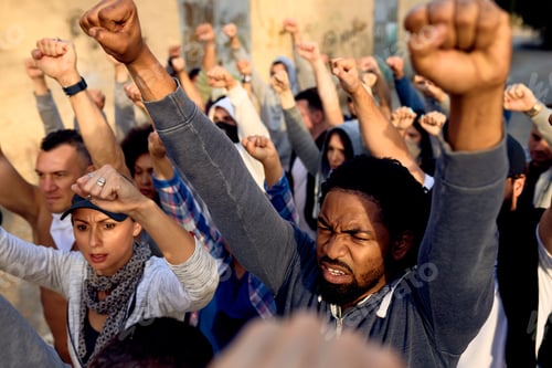 Vista previa: Displeased African American man with raised fists protesting with group of people.