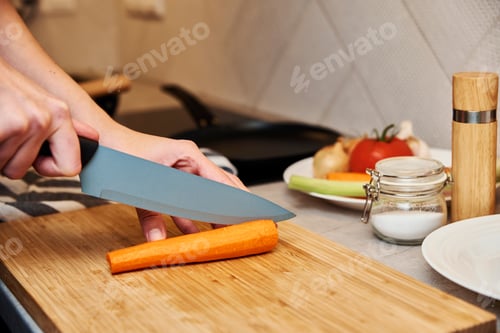 Preview: Woman chopping carrot in kitchen, close up