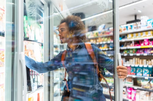 Preview: Young black man shopping for frozen food in supermarket