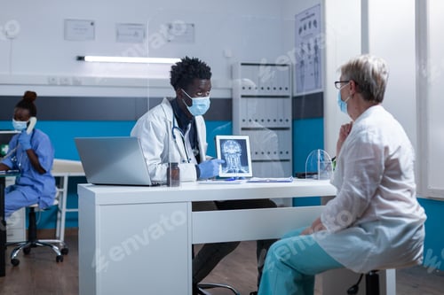 Preview: Ill retired woman being informed of bone disease while radiology expert examining MRI image scan