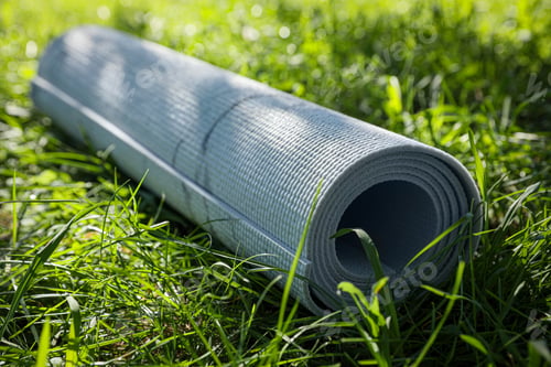 Preview: Rolled karemat or fitness mat on green grass outdoors, closeup