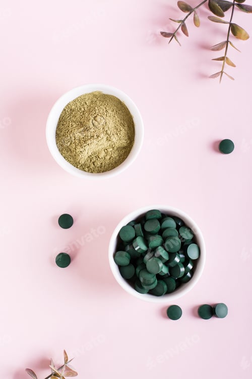 Preview: Detox and antioxidant. Matcha powder and spirulina pills in bowls on a pink. Top and vertical view