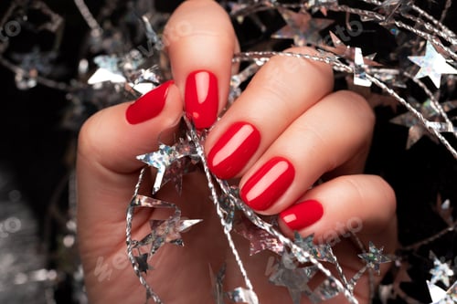 Vista previa: Mano con uñas rojas con oropel navideño