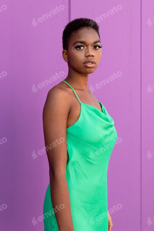 Preview: Stylish black woman with short hair in green dress in front of a lilac background