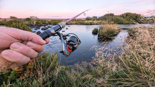 Preview: Hand holding fishing rod and reel, fishing at Corrib river at Galway, Ireland, spinning, angling, ca