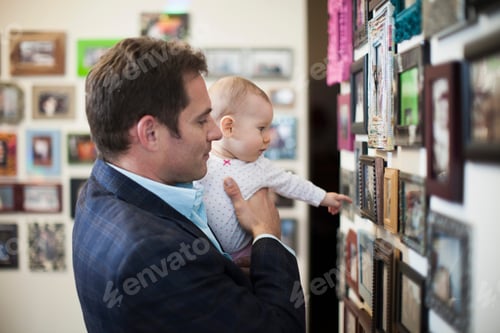 Preview: Businessman and baby looking at pictures