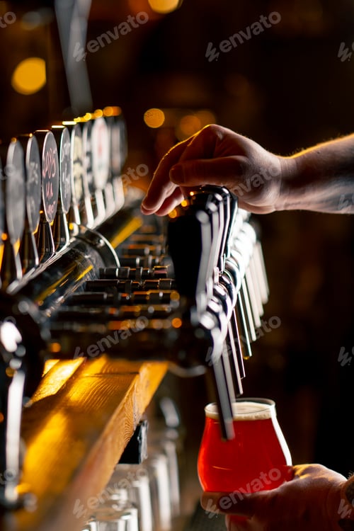 Preview: close-up in beer hall at the bar counter the bartender's hands pour light beer into a glass