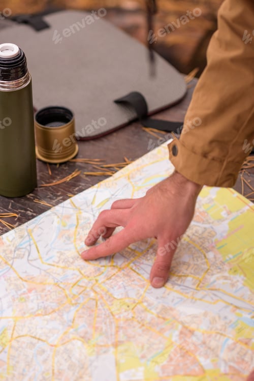 Preview: Close-up view of male hand and map on wooden table in autumn forest