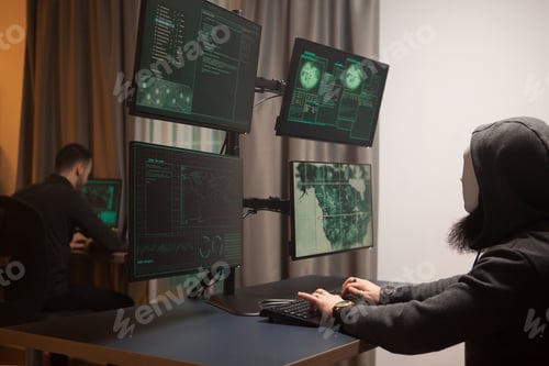 Preview: Masked and dangerous hacker in front of computer