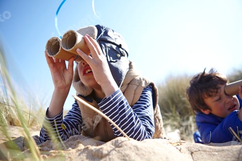Preview: Two young boys on beach, looking through pretend binoculars