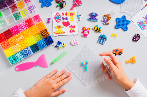 Preview: Children's hands splashing water on a thing made of aqua beads top view
