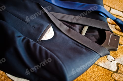 Preview: Close-up photo of a groom's suit or tuxedo on the hanger laying in the floor.