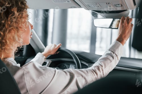 Preview: Vehicle interior. Woman with curly blonde hair is in autosalon