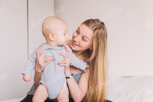 Preview: beautiful young mother hugging and lookign at adorable infant child