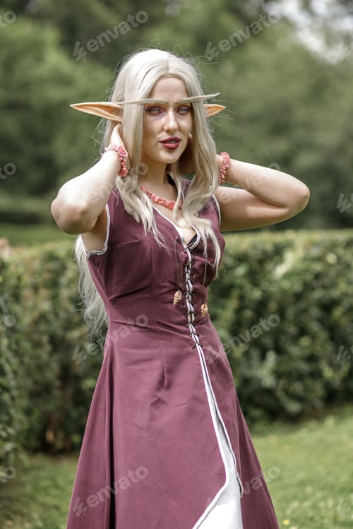 Preview: Young elf girl with blond long hair. Medieval elven princess in a burgundy dress in the forest