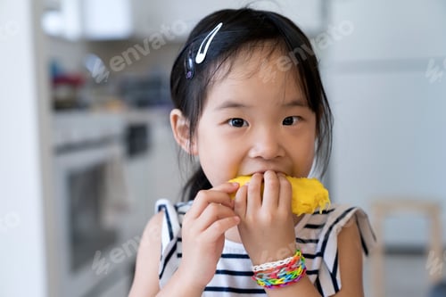 Preview: Happy little girl eating mango