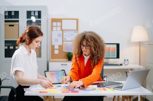 Preview: Two female designers brainstorming color palettes in a modern office. Creative teamwork, branding,