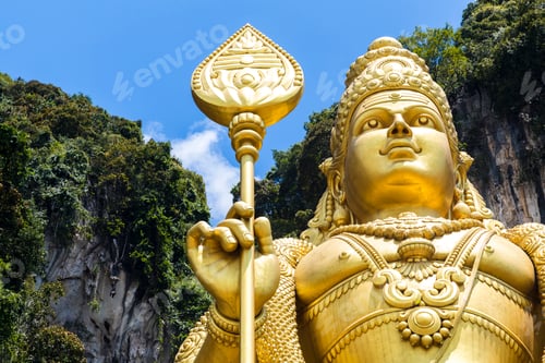 Preview: Low angle close up of colossal golden statue of Hindu deity.